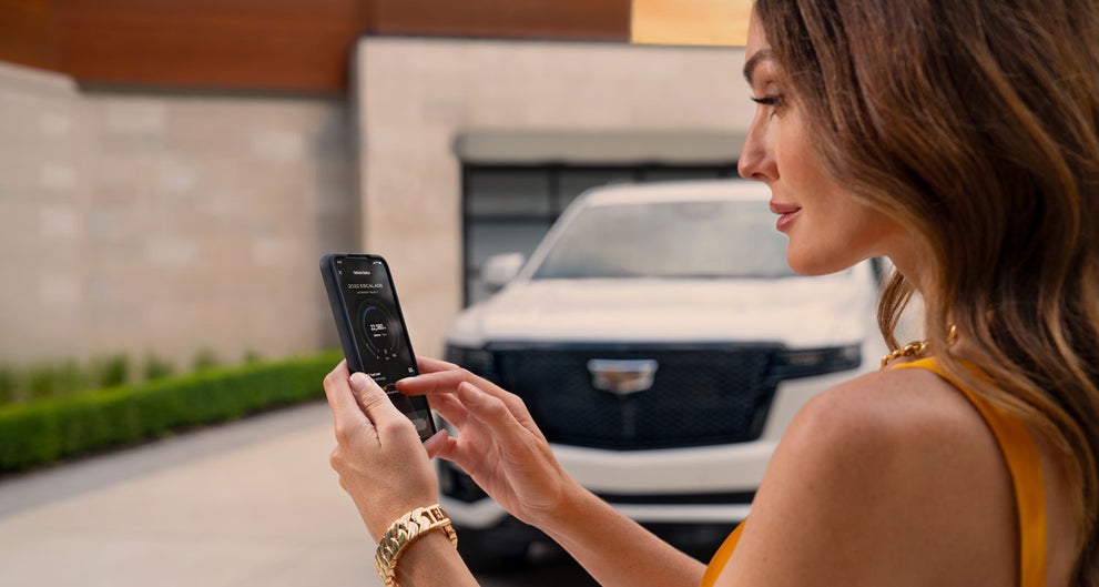 lady checking her mobile with a Cadillac vehicle background | Davidson Cadillac of Rome in Rome NY